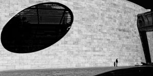 Homme se tenant debout devant un immeuble en briques blanches gigantesque. Photo de Eric Forey
