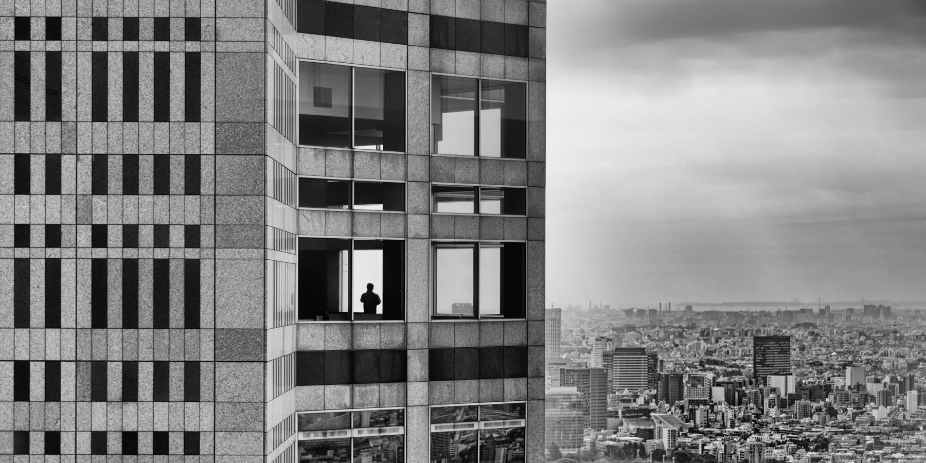 Silhouette d'homme à travers la fenêtre d'un très haut immeuble